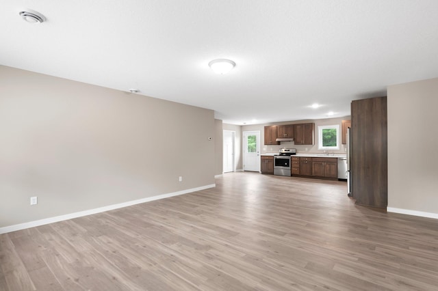 unfurnished living room with sink and light hardwood / wood-style floors