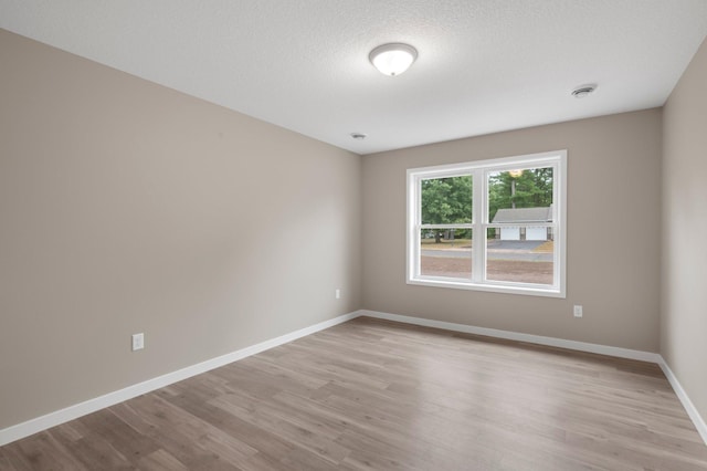 empty room featuring a textured ceiling and light hardwood / wood-style flooring