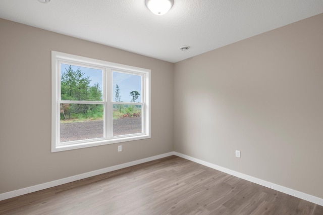 spare room featuring a textured ceiling and light wood-type flooring