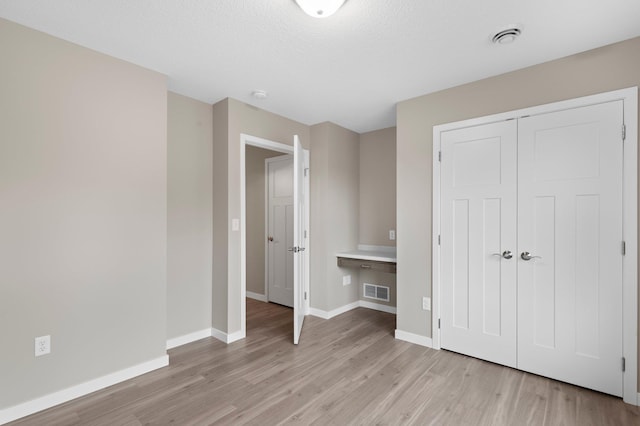 unfurnished bedroom with a closet, a textured ceiling, and light hardwood / wood-style floors