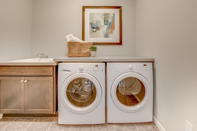 laundry area with washing machine and dryer, light tile floors, cabinets, and sink