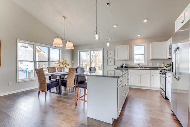 kitchen featuring dark hardwood / wood-style floors, appliances with stainless steel finishes, white cabinets, a kitchen island, and pendant lighting