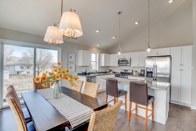 dining space with high vaulted ceiling and hardwood / wood-style flooring