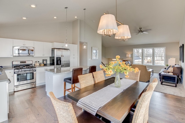 dining room featuring high vaulted ceiling, ceiling fan, and light wood-type flooring