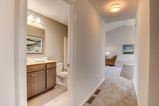 bathroom featuring vanity, lofted ceiling, tile floors, a textured ceiling, and toilet