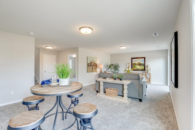 dining space featuring light carpet and a textured ceiling