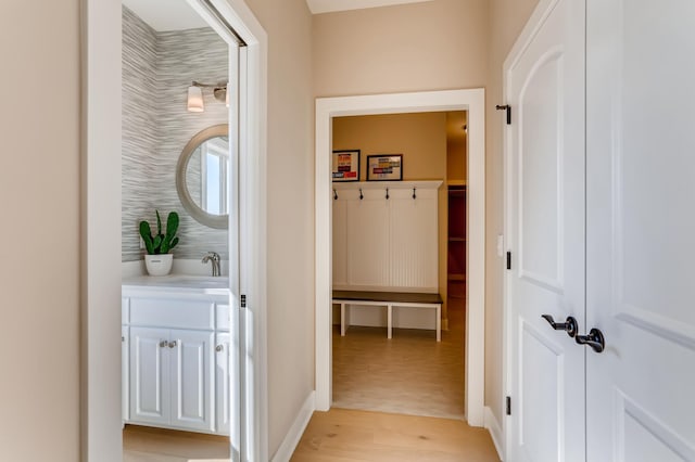 corridor with sink and light wood-type flooring