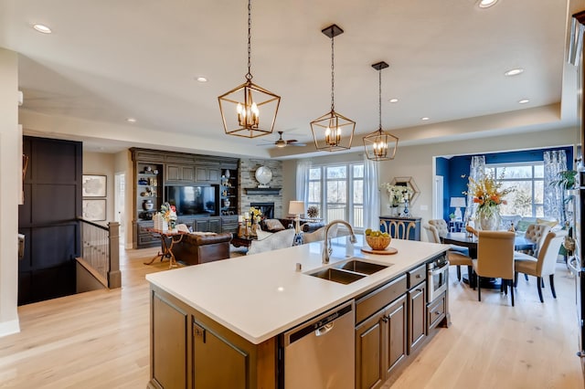 kitchen with decorative light fixtures, sink, stainless steel dishwasher, and a center island with sink