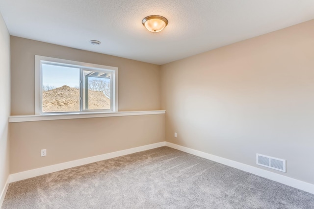 carpeted spare room with a textured ceiling