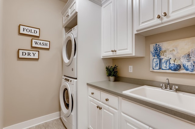 laundry room featuring sink, cabinets, and stacked washer / drying machine