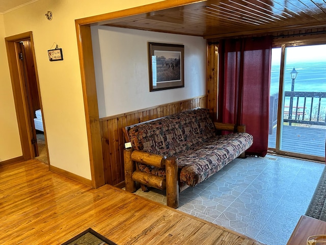 living room with light hardwood / wood-style flooring, wood ceiling, and wooden walls