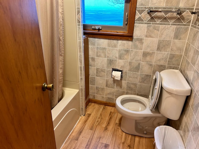 bathroom featuring toilet, tile walls, wood-type flooring, and shower / bath combo