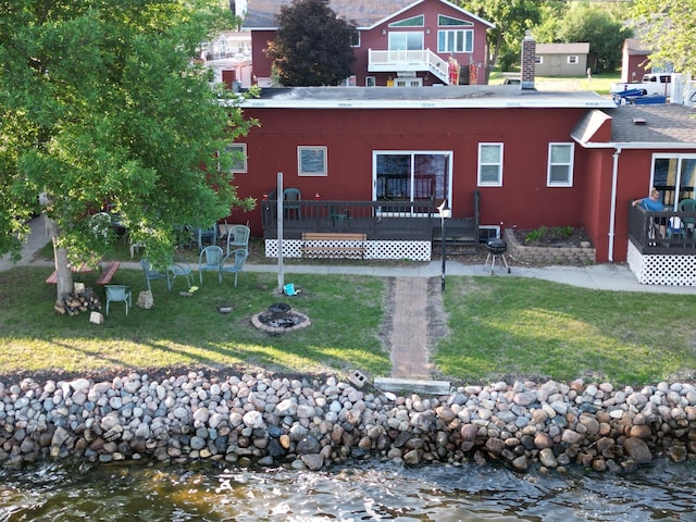 back of house with a deck with water view and a yard