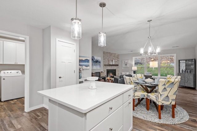 kitchen with washer / clothes dryer, a center island, a fireplace, and dark hardwood / wood-style floors