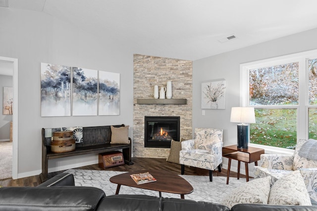 living room with a stone fireplace, wood-type flooring, and lofted ceiling