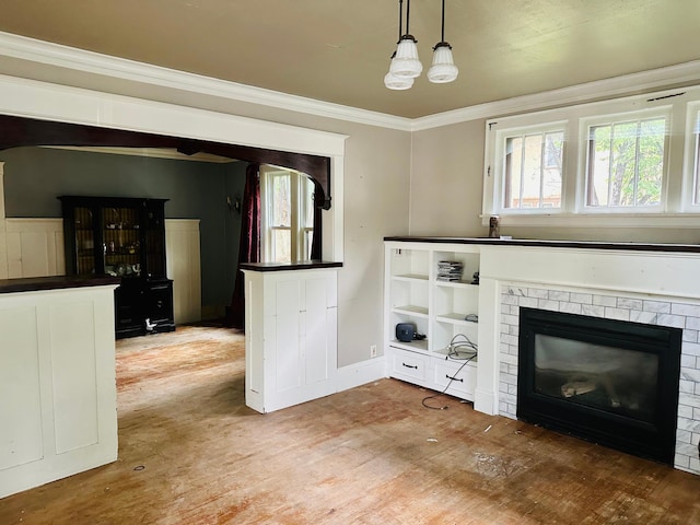 unfurnished living room with an inviting chandelier, ornamental molding, a fireplace, and hardwood / wood-style flooring