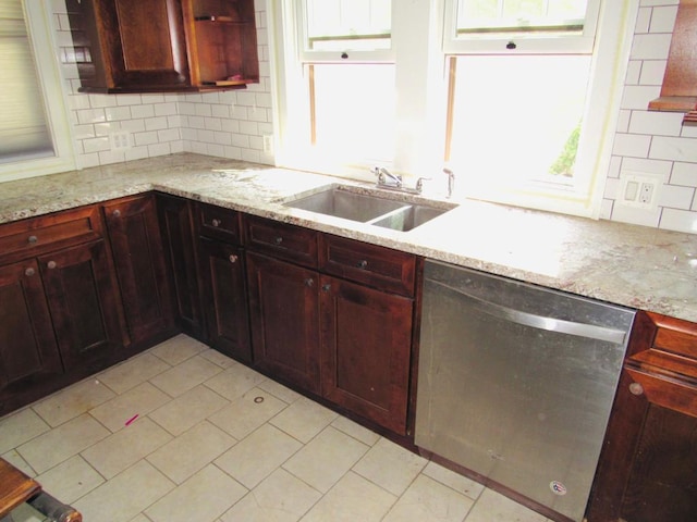 kitchen with stainless steel dishwasher, sink, tasteful backsplash, and light stone countertops