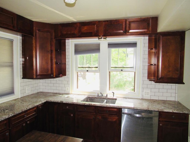 kitchen featuring light stone countertops, backsplash, stainless steel dishwasher, and sink