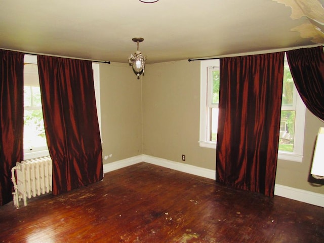 empty room with dark wood-type flooring and radiator