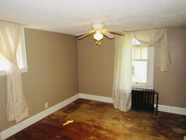 unfurnished room with radiator heating unit, ceiling fan, a textured ceiling, and dark hardwood / wood-style flooring