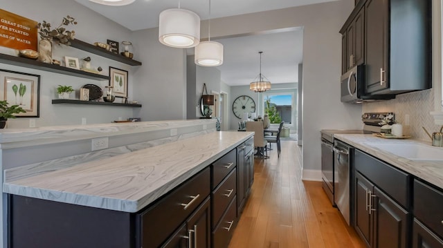 kitchen with stainless steel appliances, light stone countertops, pendant lighting, and light wood-type flooring