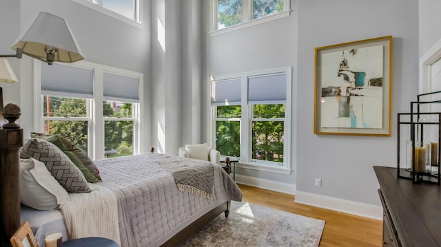 bedroom featuring a towering ceiling and light wood-type flooring