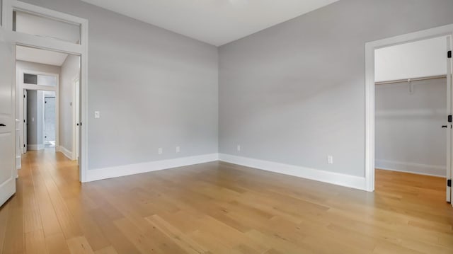 unfurnished bedroom with a spacious closet, a closet, and light hardwood / wood-style floors