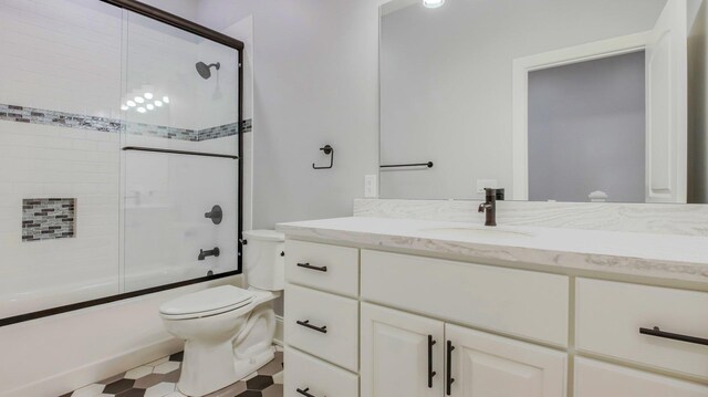 full bathroom with vanity, bath / shower combo with glass door, and toilet