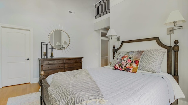 bedroom featuring a towering ceiling and light hardwood / wood-style flooring