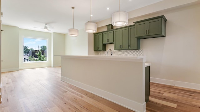 kitchen featuring pendant lighting, light wood-type flooring, backsplash, and ceiling fan