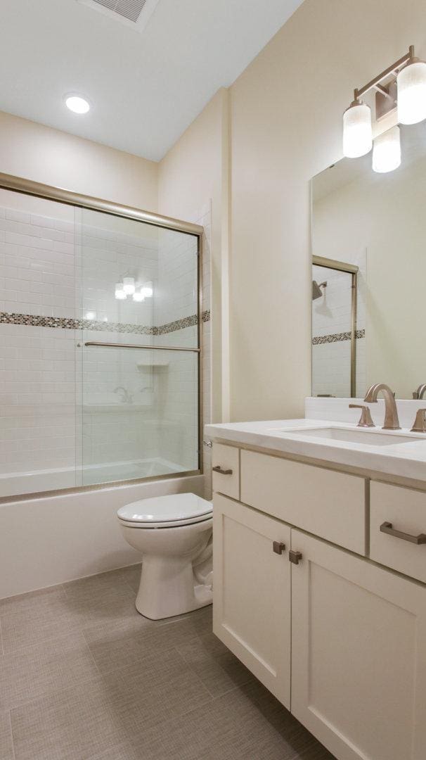 full bathroom with enclosed tub / shower combo, vanity, and toilet