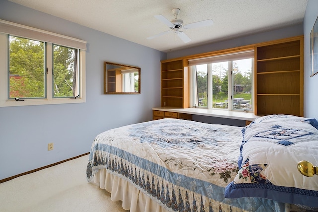 carpeted bedroom featuring multiple windows, a textured ceiling, and ceiling fan