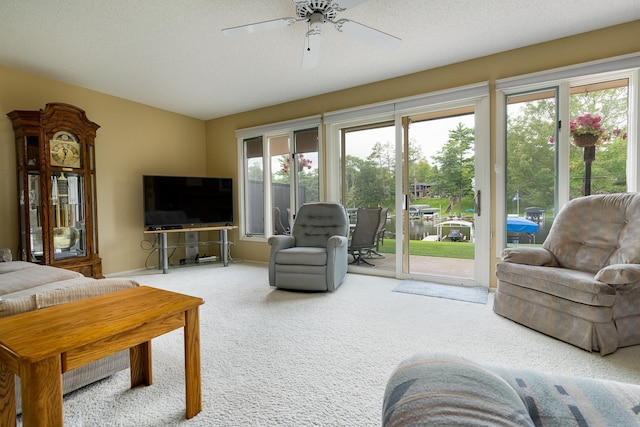 carpeted living room with ceiling fan, a textured ceiling, and a wealth of natural light