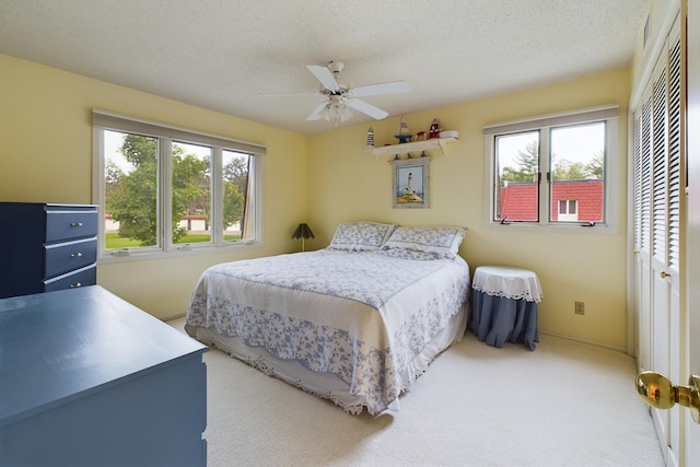 carpeted bedroom featuring ceiling fan, a textured ceiling, a closet, and multiple windows