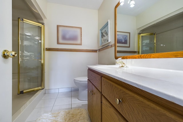 bathroom featuring vanity, toilet, a shower with door, and tile patterned floors