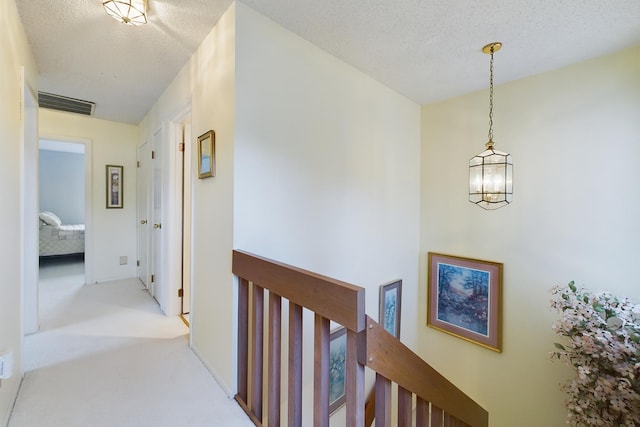 corridor with light colored carpet and a textured ceiling