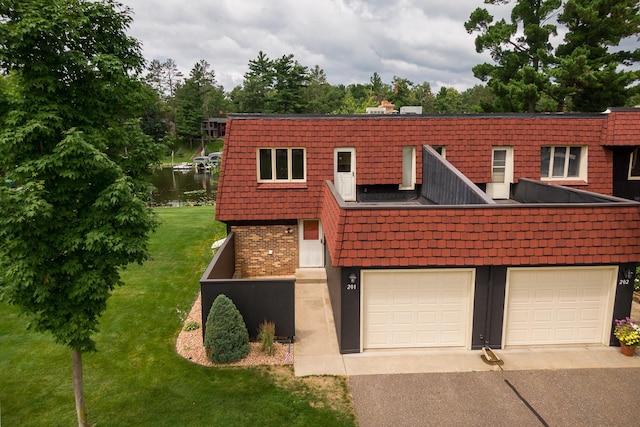 view of front of property featuring a front yard, a garage, and a water view