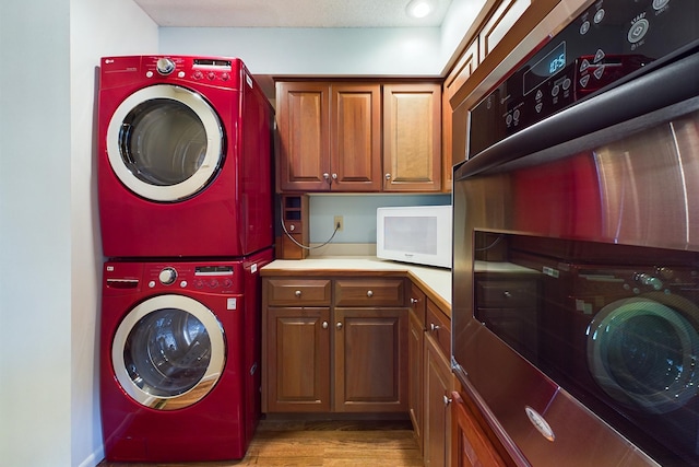 laundry room with cabinets, light hardwood / wood-style flooring, and stacked washer and dryer