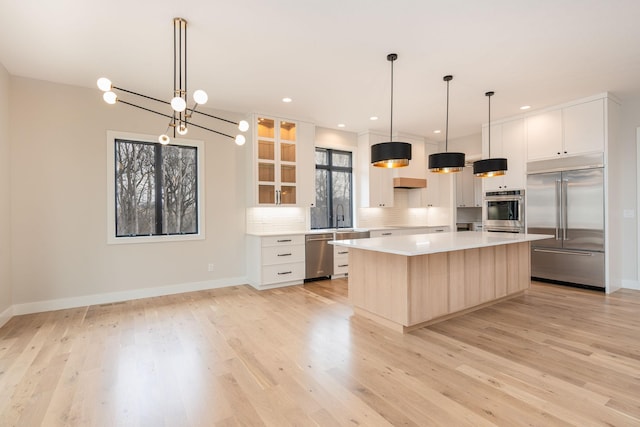 kitchen with white cabinetry, pendant lighting, stainless steel appliances, and a kitchen island