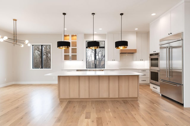 kitchen featuring decorative backsplash, light countertops, a center island, and stainless steel appliances