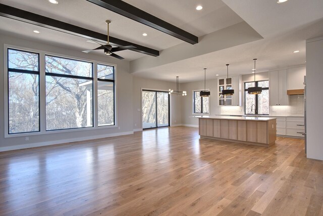 kitchen featuring light wood-type flooring, modern cabinets, a spacious island, backsplash, and open floor plan