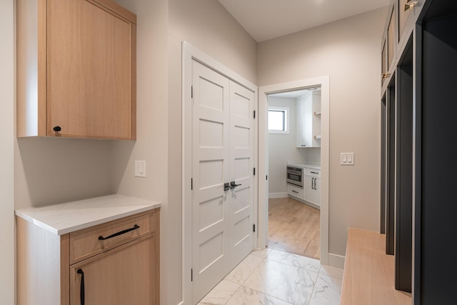 hallway with marble finish floor and baseboards