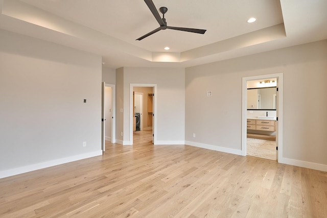 unfurnished bedroom featuring light wood finished floors, recessed lighting, a raised ceiling, and baseboards