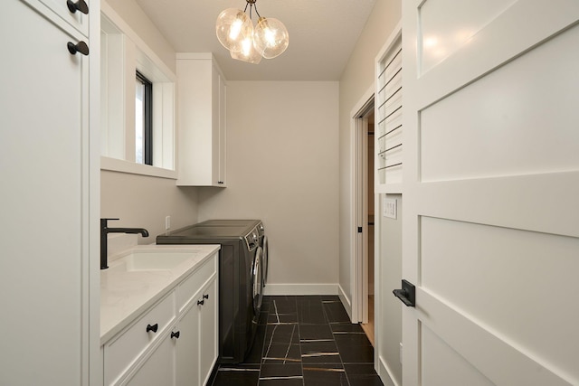 laundry area featuring a notable chandelier, a sink, cabinet space, separate washer and dryer, and baseboards