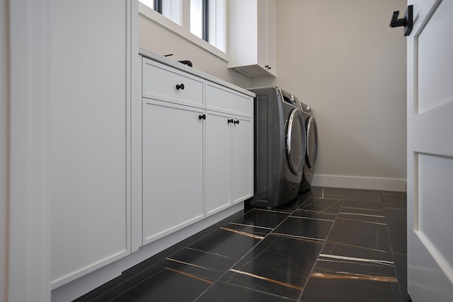 washroom with washer and clothes dryer, cabinet space, baseboards, and dark tile patterned flooring