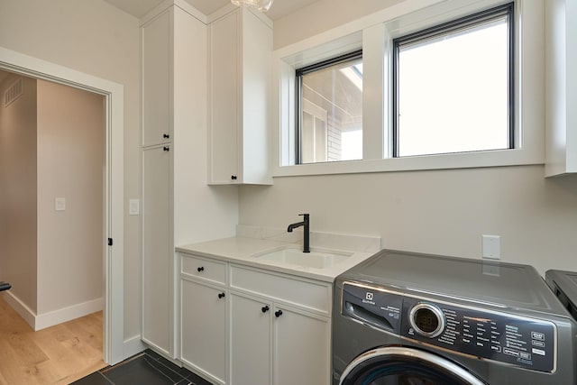 laundry room with baseboards, washing machine and clothes dryer, cabinet space, dark wood-style flooring, and a sink