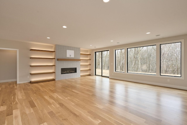 unfurnished living room featuring recessed lighting, light wood-type flooring, baseboards, and a fireplace