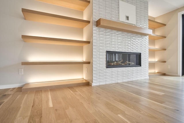 unfurnished living room with visible vents, wood finished floors, baseboards, and a tile fireplace