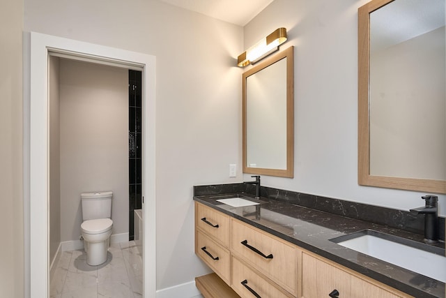 bathroom with double vanity, marble finish floor, toilet, and a sink