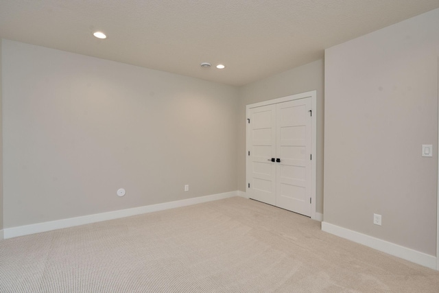 spare room featuring recessed lighting, baseboards, and light colored carpet